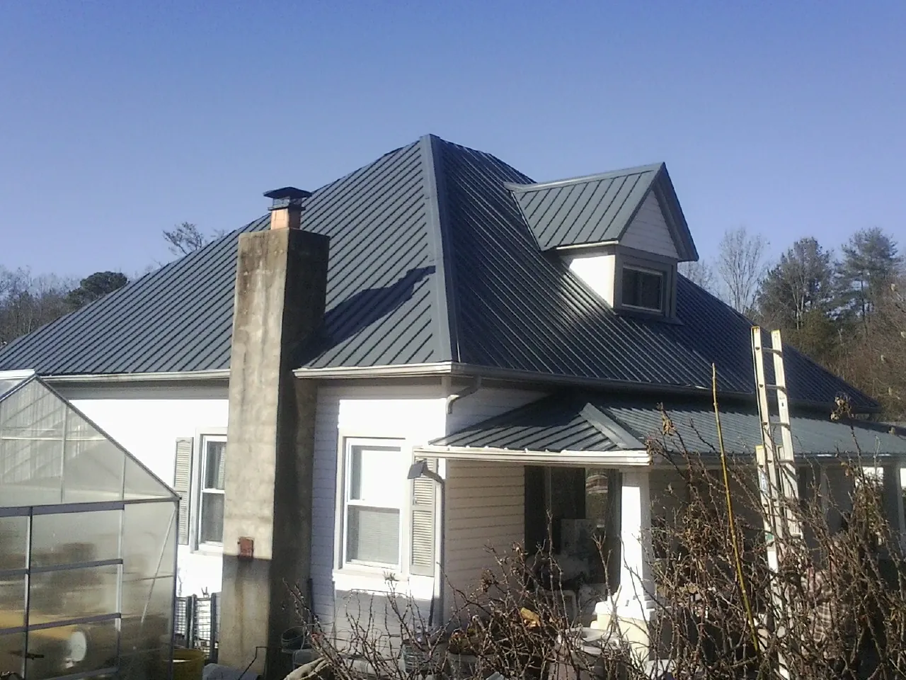 Dark blue standing seam metal roof on a white farmhouse with dormer — Slate & Tile Roof Repair by Roofing Brothers in Royston