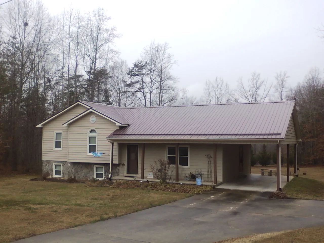 Burgundy metal roof on a tan split level home with an attached carport in Royston