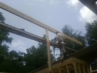 Carpenter setting a ridge beam over a new addition frame — Ice Dam Removal by Roofing Brothers in Royston