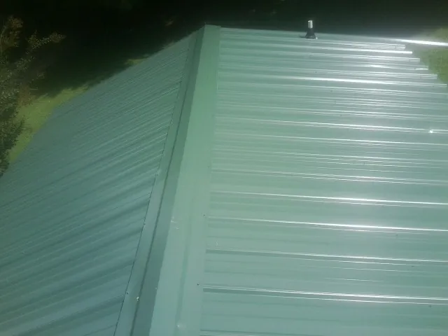 New green metal panels meeting at the ridge of a roof — Flat Roof Repair work by our crew in Royston