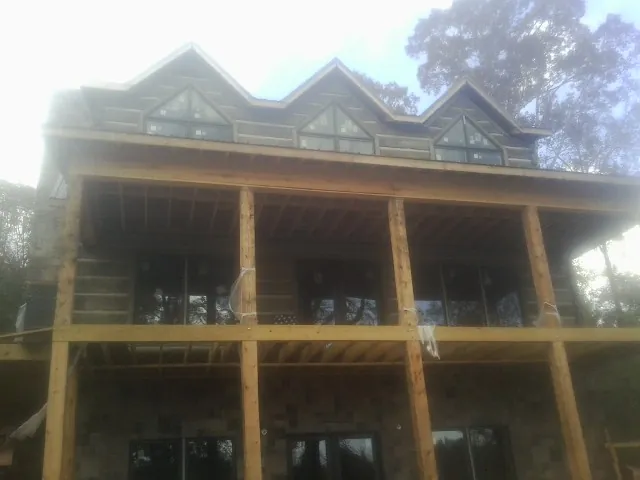 Dormers and porch framing on a large log home under construction — Roof Coating work by our crew in Royston