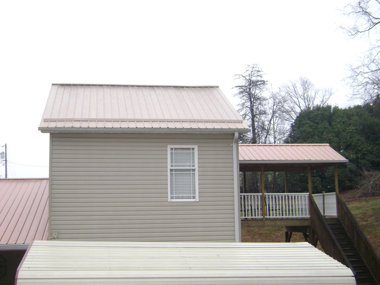 Tan metal roofs on a two story addition and attached porch, from a Roof Replacement job in Royston