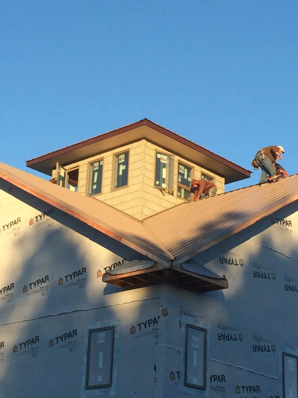 Roofers working around a rooftop cupola on a new metal roof at sunset — Roof Waterproofing in Royston by Roofing Brothers